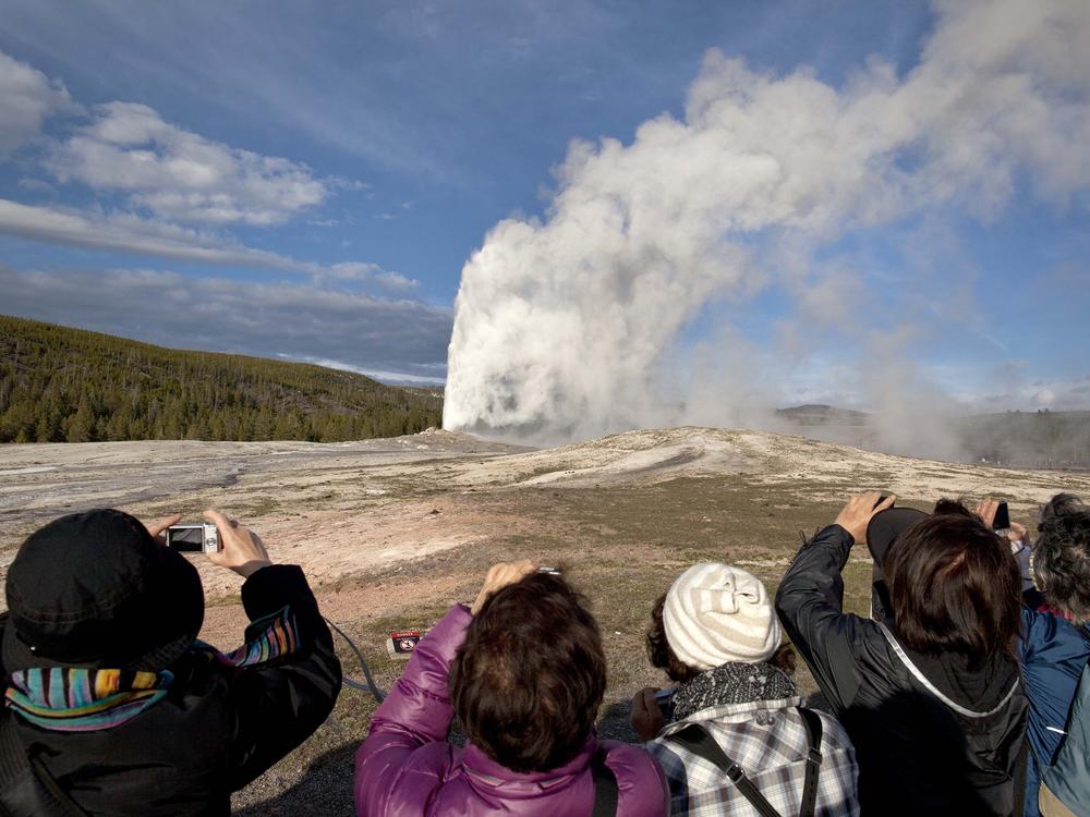 Tourists are seen photographing an eruption of Old Faithful at Yellowstone National Park in this 2011 file photo. On Thursday, a man was killed in an exchange of gunfire with law enforcement park rangers after he was reported to have a weapon and issuing threats, according to the National Park Service.