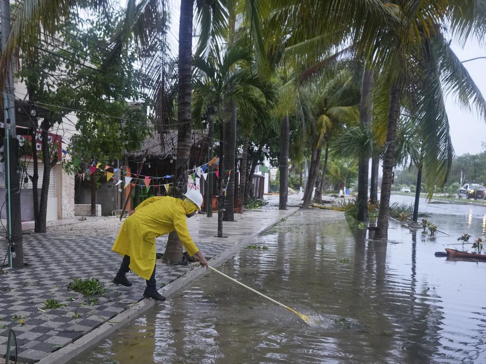 A man unclogs a drain in the aftermath of Hurricane Beryl, in Tulum, Mexico, on Friday.