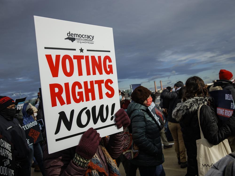 A person holds a sign that says 