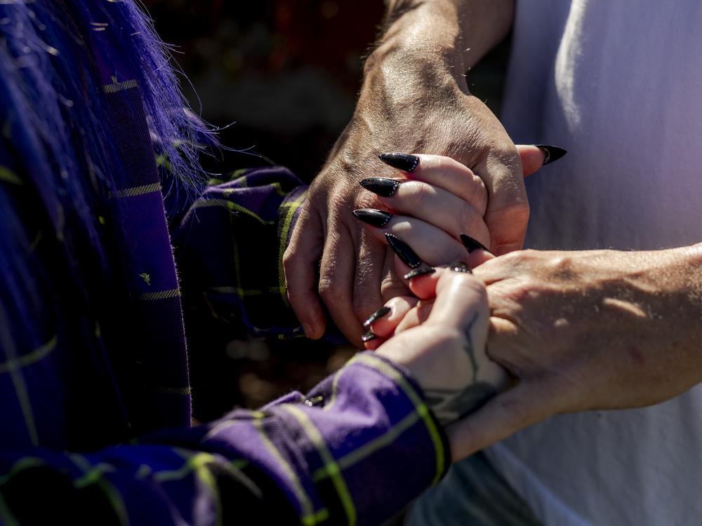 Randee Noggle and her husband, Adam hold hands at her home in Taylor, Mich. on June 30, 2024. The family fell on hard times when his income working in the restaurant industry dropped during the pandemic. That’s when Noggle found EasyKnock.<br>