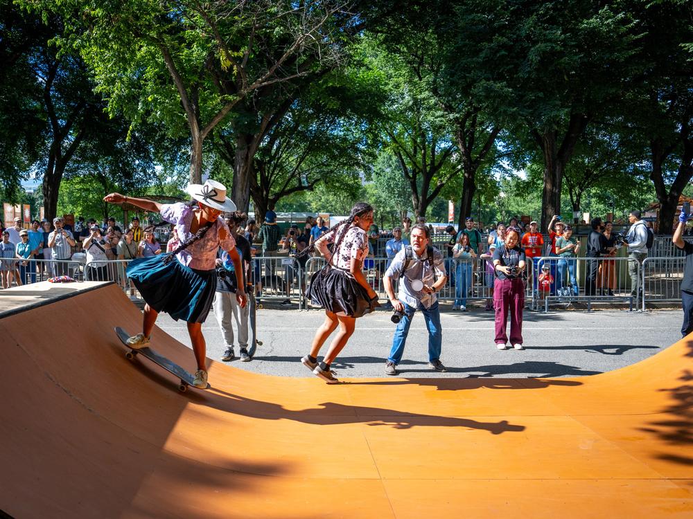 Bolivian women skateboarders — wearing traditional garb — demonstrate their skills on the half pipe. 