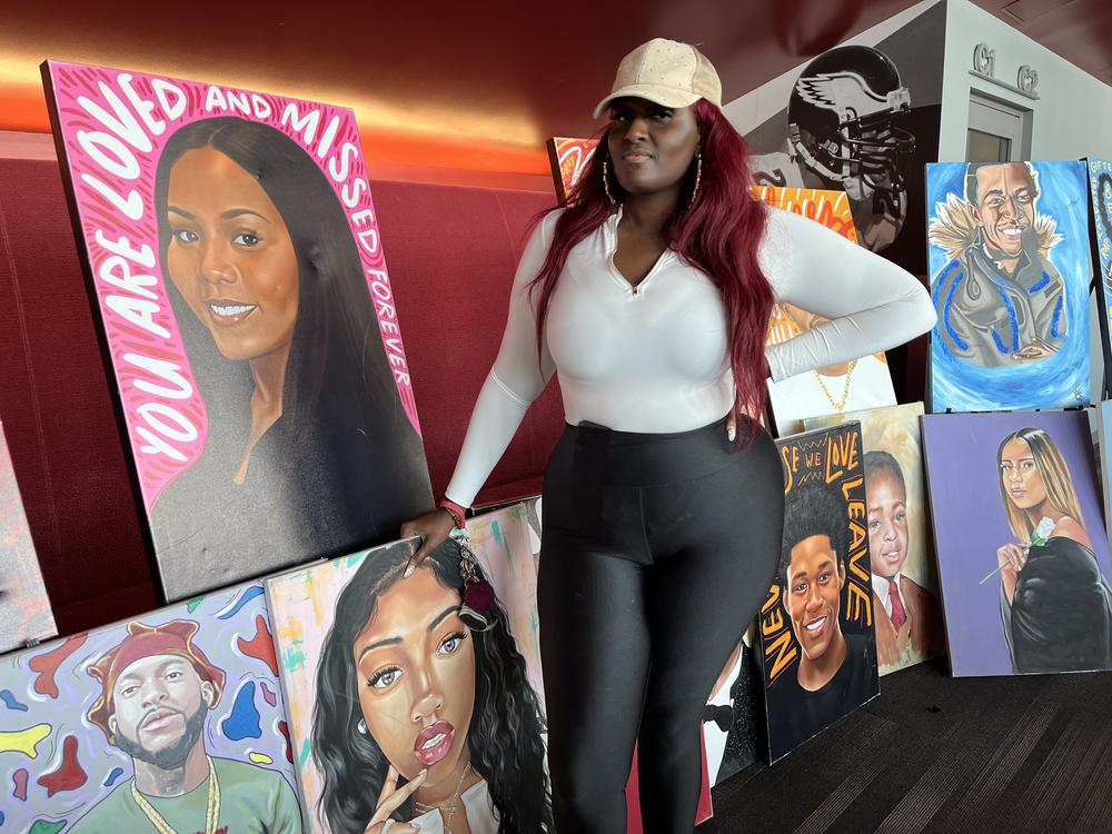 Zarinah Lomax stands beside portraits she commissioned, mostly of young people who died from gunfire. “The purpose is not to make people cry,” Lomax says. “It is for families and for people who have gone through this to know that they are not forgotten.” 