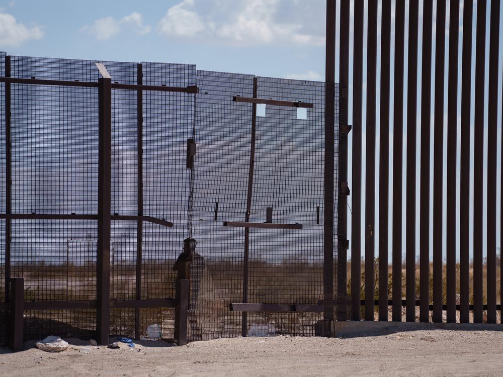 A man attempting to cross into the U.S. stands next to the border wall in Ciudad Juarez, Chihuahua state, Mexico, as seen from Sunland Park, N.M., on Saturday, June 29, 2024. 