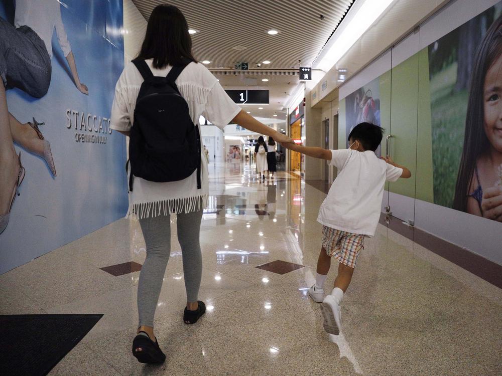 Pamela Lam plays with her son on the way to school in Hong Kong, July 3, 2020. Lam's 6-year-old son fell in love with the Hong Kong protest anthem, <em>Glory to Hong Kong</em>, the first time he heard it and sings it often. But because of a sweeping new national security law, singing it in public is now risky. Lam agreed to be photographed only if her face was not shown, fearing possible retribution from authorities. 