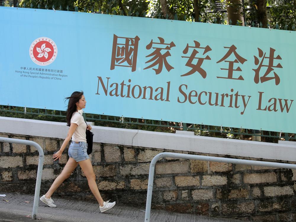 A woman walks past a promotional banner of the national security law for Hong Kong, in Hong Kong, June 30, 2020. China imposed the law that allows authorities to crack down on what they deem subversive and secessionist activities in Hong Kong.