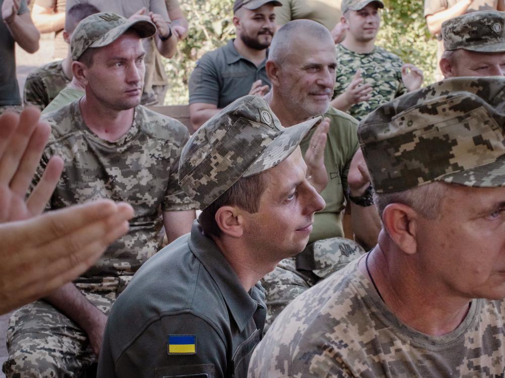 Soldiers listen as Bandura player Maria Petrovska plays as part of a concert for soldiers near the front lines in eastern Ukraine's Donbas region.