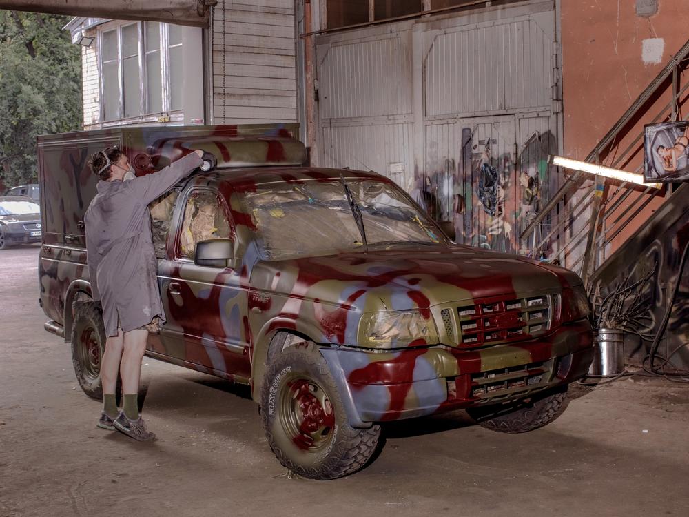 A painter adds dark red spots to a truck to camouflage with the reddish dirt and mud often found in Ukraine's east and south.