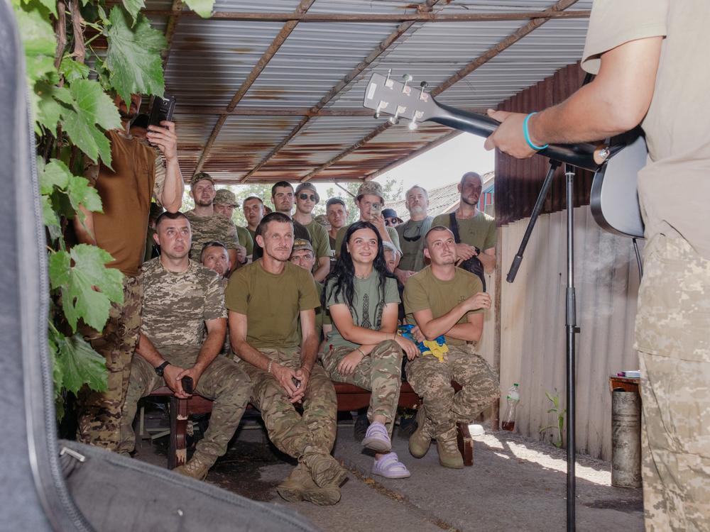 Ukrainian soldiers watch a music performance in a driveway of the home where currently being used as a base, on the front in eastern Ukraine.