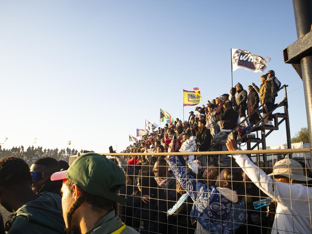Spectators in the grand stands cheer as the spinning show begins, at Wheelz N Smoke arena, on July 7, in Johannesburg.