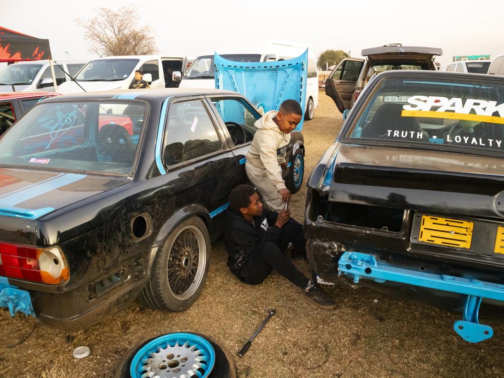 Young boys imitate the mechanics working on the spinning cars at the Wheelz N Smoke arena, July 7, in Johannesburg.
