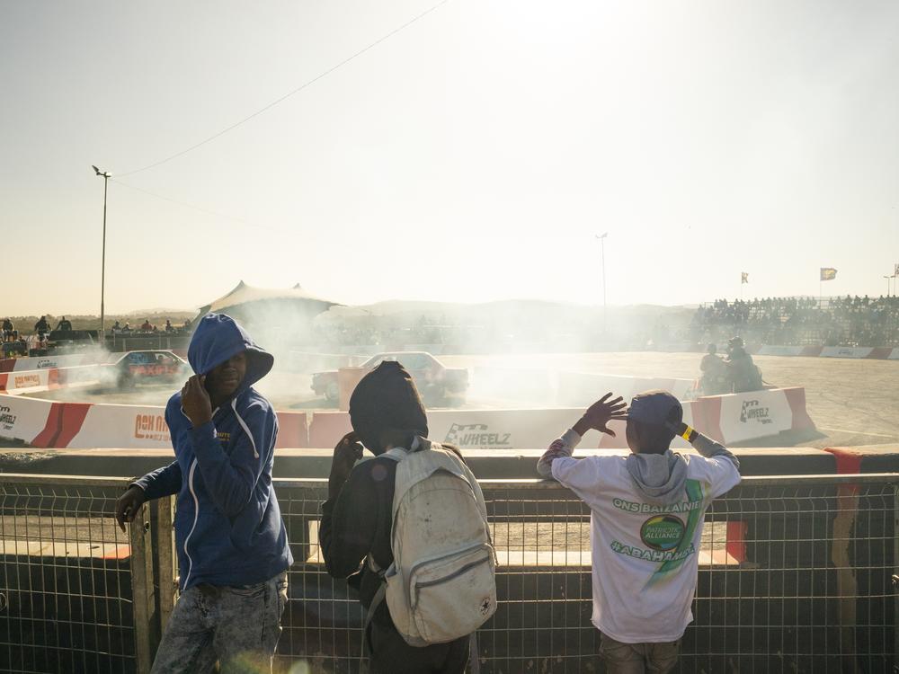 Three young spectators cover their faces from rubber debris and smoke at the spinning field, at Wheelz N Smoke arena, on July 7, in Johannesburg, South Africa.