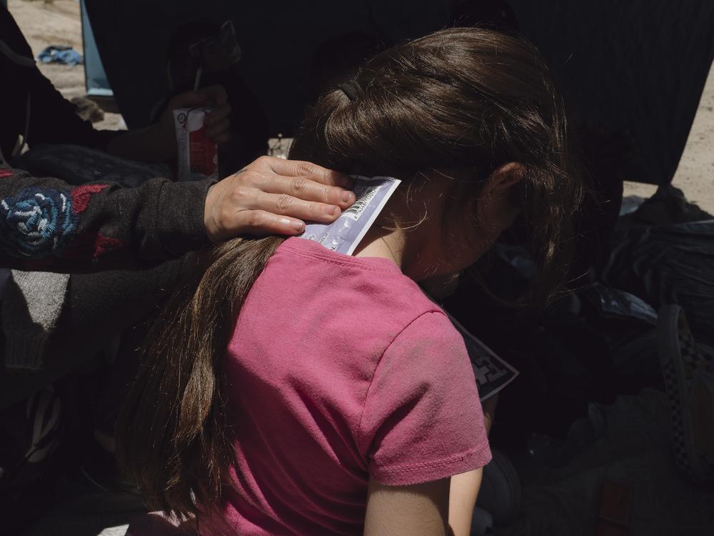 A mother tries to cool her child with an icepack, after crossing the desert in the San Diego sector of the U.S.-Mexico border during a heat wave.