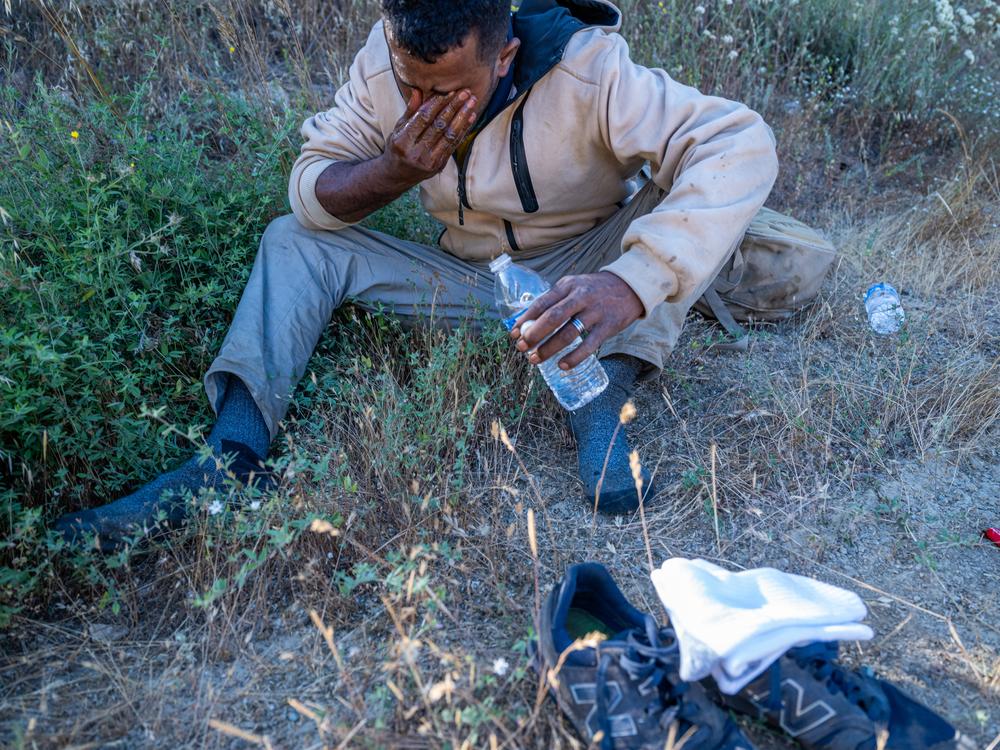 Taleb, an asylum seeker from Mauritania, cries a bit as he rests in the shade after crossing the border in the San Ysidro Mountains near San Diego, Calif. Even in the early hours of the morning, triple-digit temperatures make an already dangerous journey even more risky. 