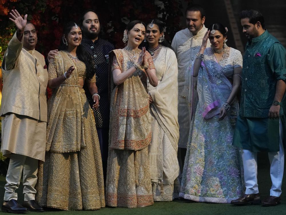 Reliance Industries Chairman Mukesh Ambani (left) waves to photographers as he poses with his family members on the occasion of engagement of his son Anant Ambani (third from left), with Radhika Merchant (second from left) during a ceremony in Mumbai, on Jan. 19, 2023.