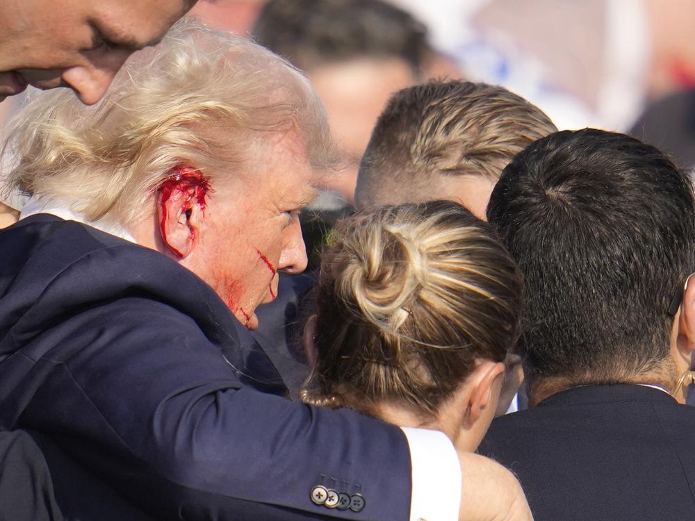 Republican presidential candidate former President Trump is surrounded by U.S. Secret Service agents as he is helped off the stage at a campaign rally in Butler, Pa.