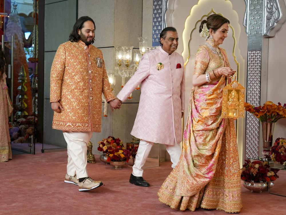 Billionaire Mukesh Ambani (center) takes his son Anant Ambani by the hand as they walk with Nita Ambani (right) at the wedding in Mumbai on Friday.