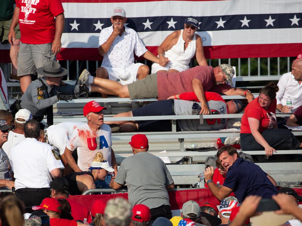 Trump supporters are seen covered with blood in the stands after guns were fired at Republican candidate Trump.