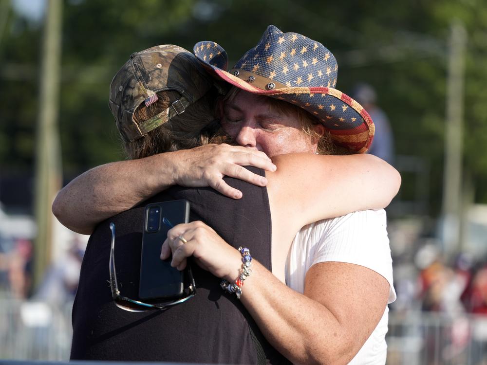 People hug after Republican presidential candidate former President Trump was helped off the stage.
