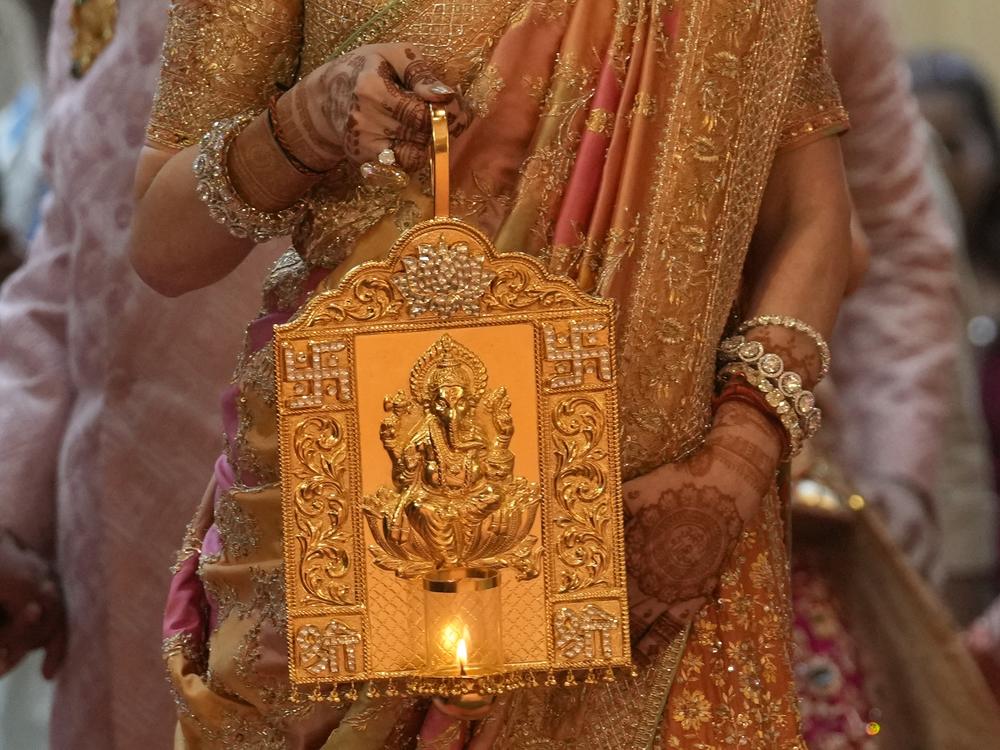 Nita Ambani, wife of Asia's richest man, Mukesh Ambani, arrives holding a lamp with an image of elephant-headed Hindu god Ganesha, for the wedding of their youngest son, Anant Ambani in Mumbai on Friday.