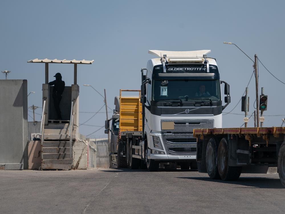 An Israeli border guard watches as trucks drive from Gaza into the Gaza side of the Kerem Shalom border crossing. The trucks are loaded and then return to Gaza.