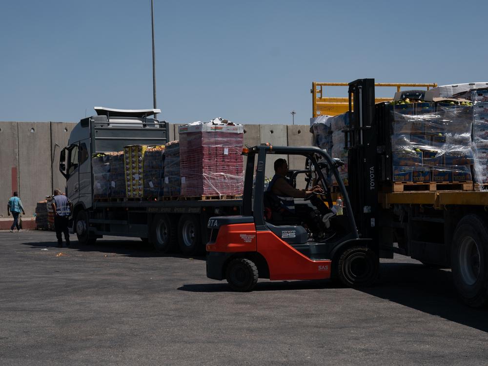 A forklift driver loads a truck with food on the Israeli side of the Kerem Shalom border crossing with southern Gaza on Wednesday. Israel says food is going into southern Gaza daily but is piling up on the Gaza side because the United Nations and aid groups aren't distributing it in a timely fashion. The U.N. says Israeli military operations and other war-related obstacles hamper its efforts.