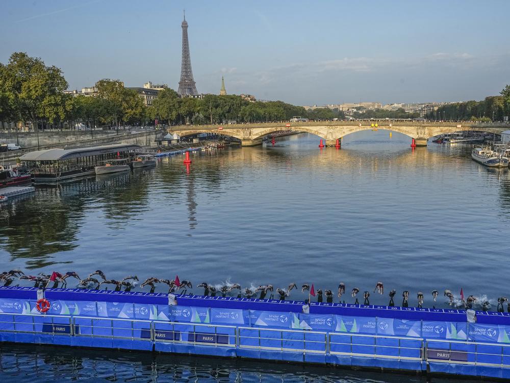 Athletes dive into the Seine River from the Alexander III bridge on the start of the first leg of the women's triathlon test event for the 2024 Paris Olympics in Paris in August 2023.