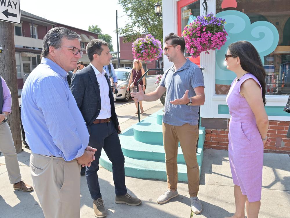 From left, Pennsylvania Secretary of Transportation Mike Carroll, U.S. Secretary of Transportation Pete Buttigieg, Dave Brown, owner of Splits and Giggles Cafe, and Lancaster, Pa., Mayor Danene Sorace speak next to one of the city's new protected bike lanes in June 2024. 