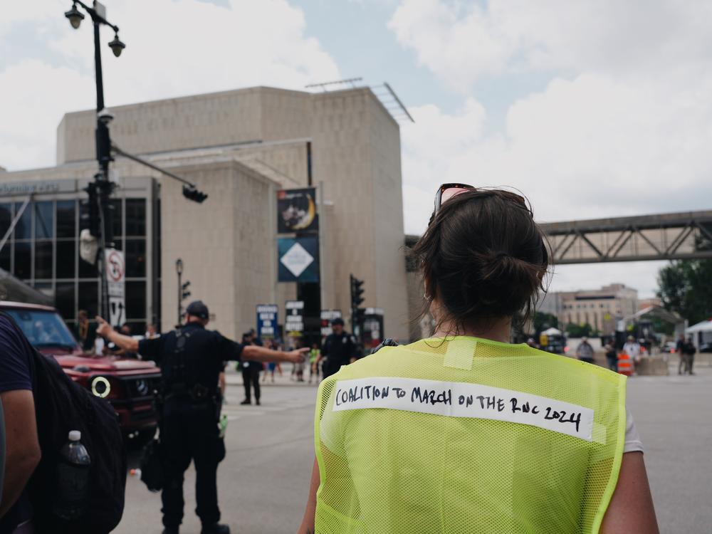 A guide waits as a police officer clears the road for protesters with March on the RNC during the first day of the 2024 Republican National Convention in Milwaukee on Monday.