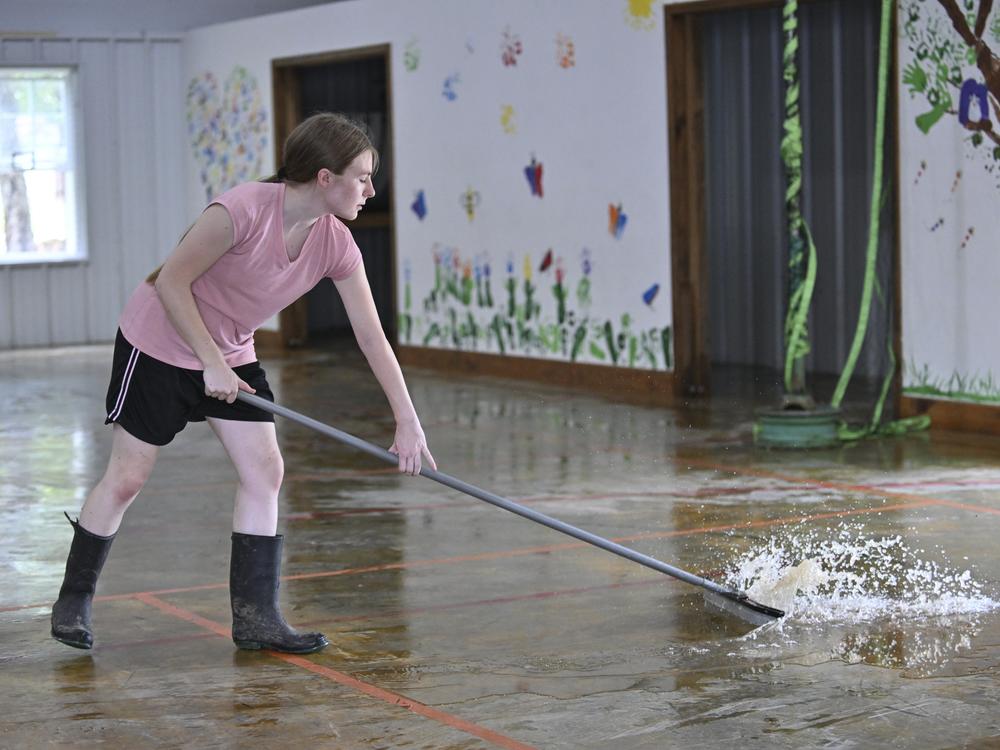 Ashley Joiner, 17, uses a squeegee to push water out of the fellowship hall at the Christian Church in Flippin, Ark., after it flooded on Wednesday.