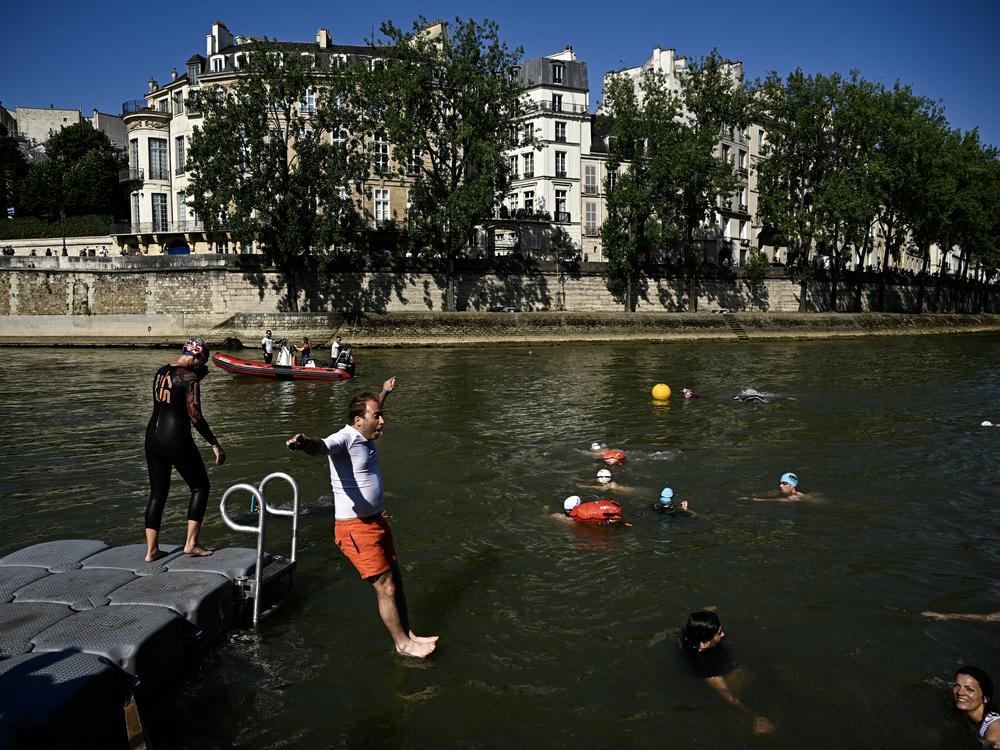 People jump into the Seine River in Paris on July 17, after Mayor Anne Hidalgo swam in the river to demonstrate that it is clean enough to host the outdoor swimming events at the Paris Olympics later this month.