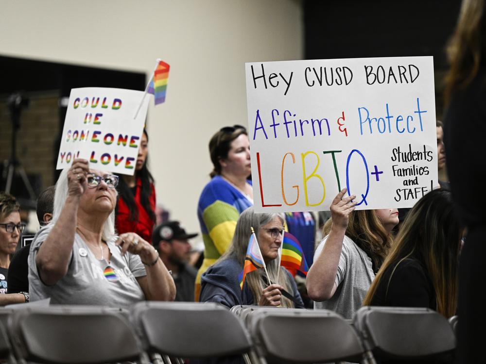 Parents, students, and staff of Chino Valley Unified School District hold up signs in favor of protecting LGBTQ+ policies at Don Antonio Lugo High School, in Chino, Calif., in June 2023. California Gov. Gavin Newsom signed a law Monday barring school districts from passing policies that require schools to notify parents if their child asks to change their gender identification.