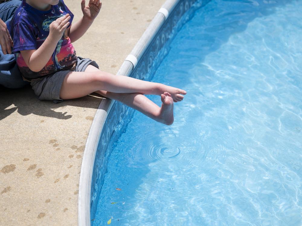 Sam plays poolside with help from his mom.