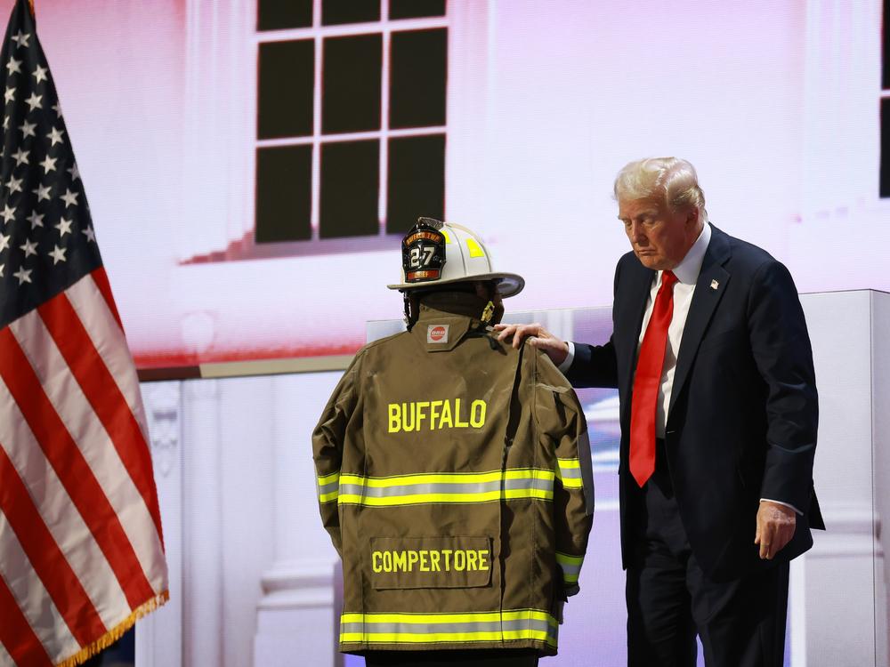 Republican presidential nominee, former President Donald Trump, embraces the firefighter uniform of Corey Comperatore as he speaks on stage on the fourth day of the Republican National Convention in Milwaukee. 