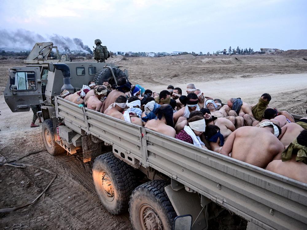 Israeli soldiers stand by a truck with Palestinian detainees in the Gaza Strip, Dec. 8, 2023.