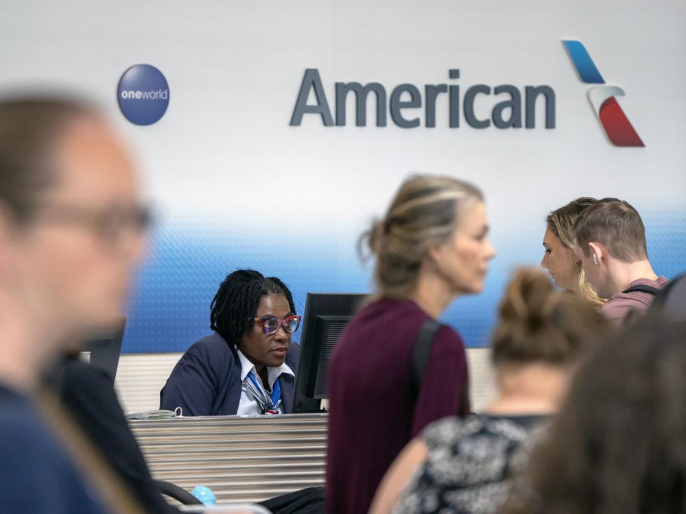 Travelers stand in line at an American Airlines counter at Reagan National Airport on Friday, July 19, 2024, in Arlington, Va. 