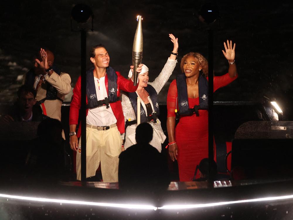 Rafael Nadal holds the Olympic torch alongside Serena Williams on a boat on the river Seine ahead of lighting the Olympic cauldron during the opening ceremony.