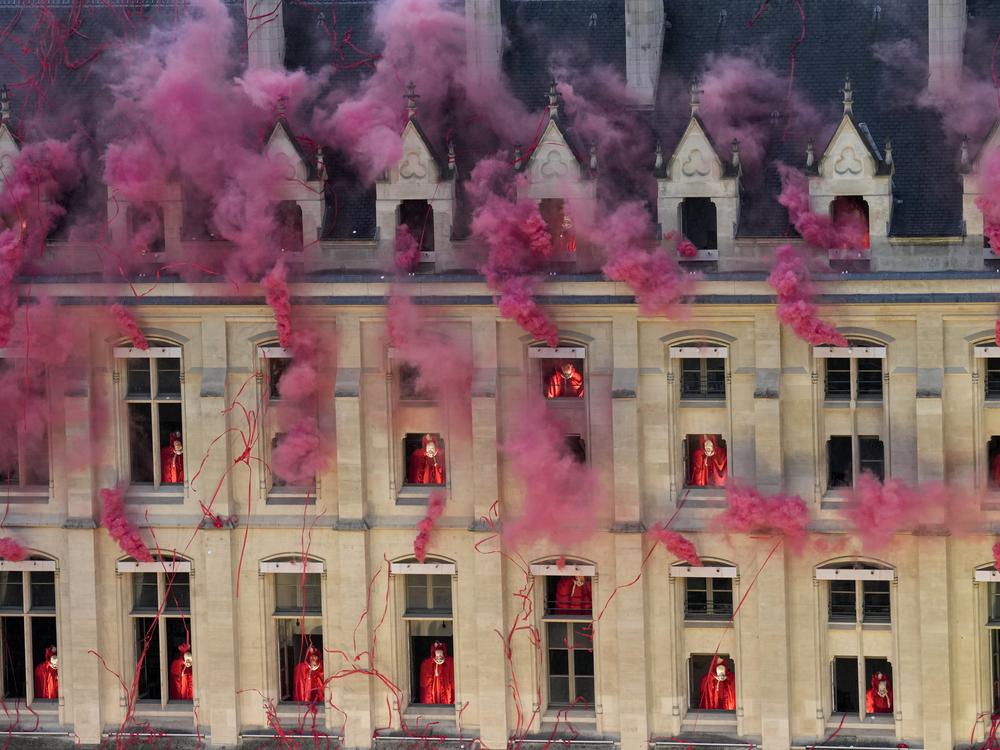 Smoke billows near windows as performers participate during the opening ceremony.
