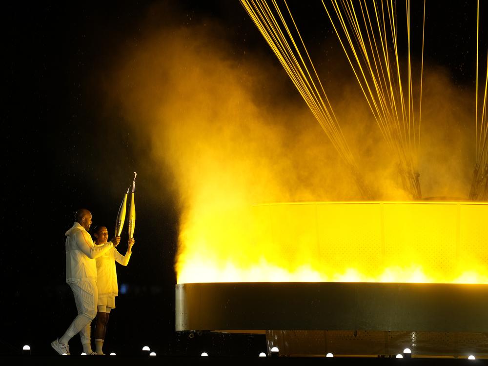 The cauldron is lit by torch bearers Marie-Jose Perec and Teddy Riner.