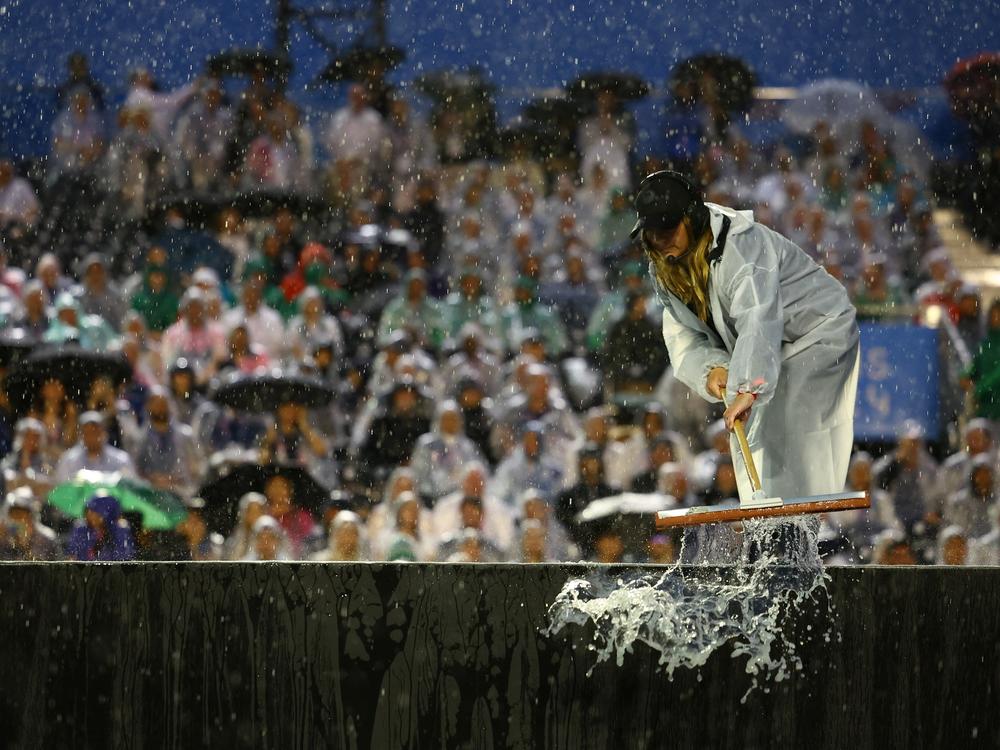 A worker sweeps rain water at the Trocadero.