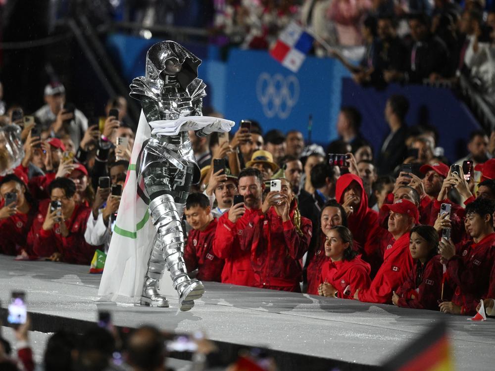 The horsewoman walks with the Olympic flag past athletes at the Trocadero.