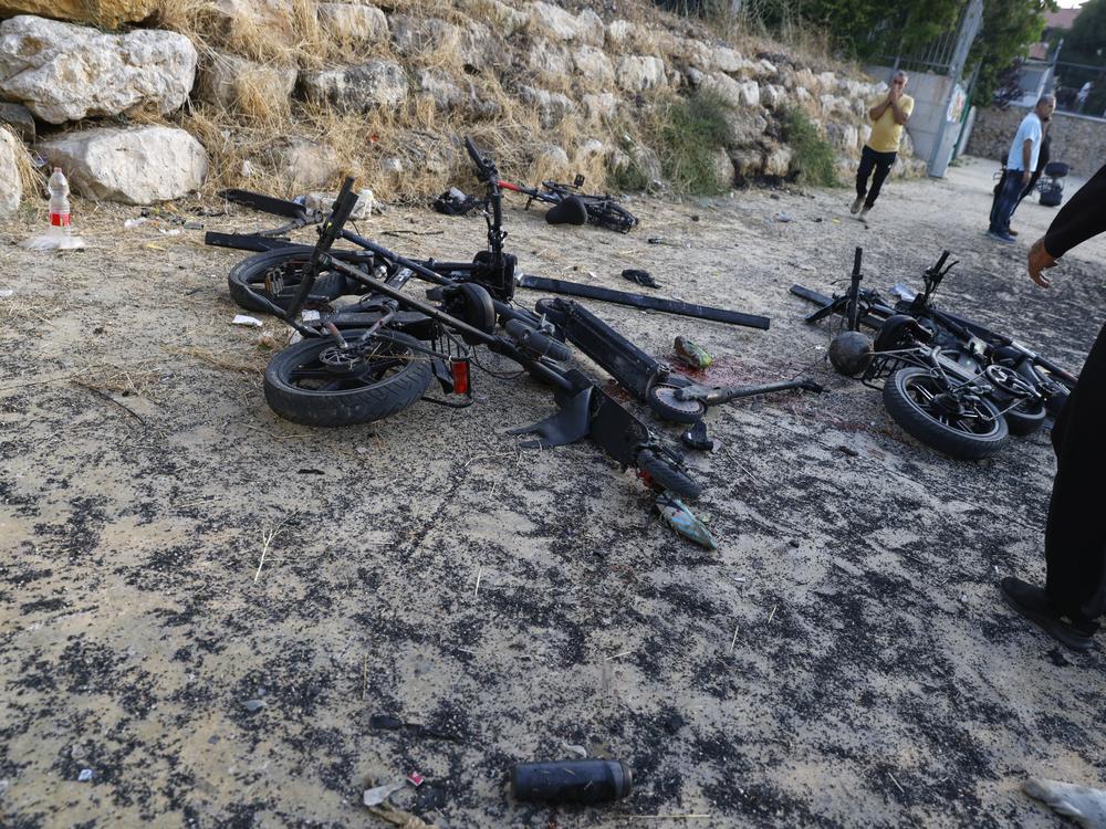 People stand by damaged bicycles at a site where a reported strike from Lebanon fell in Majdal Shams village in the Israeli-controlled Golan Heights area on Saturday.