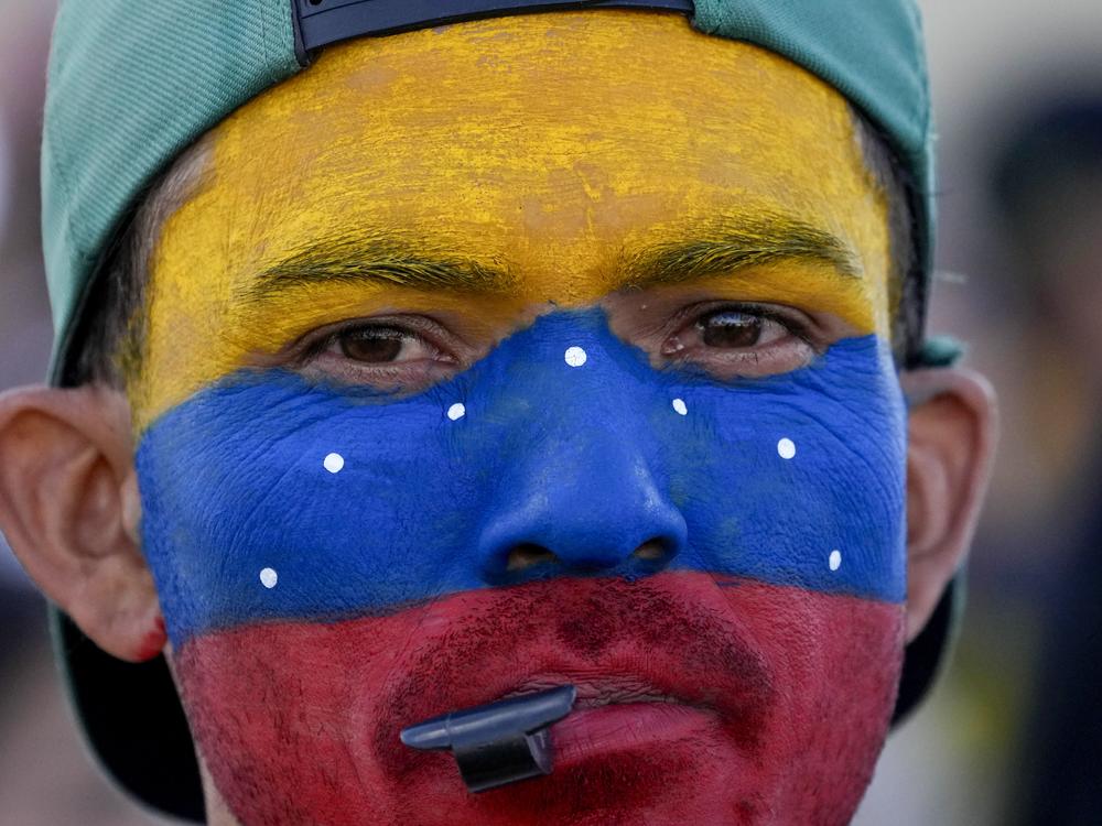 A Venezuelan living in Brasilia, Brazil, with his face painted in the colors of his nation's flag, gathers with fellow Venezuelans on the day of their nation's presidential election, Sunday, July 28, 2024. 