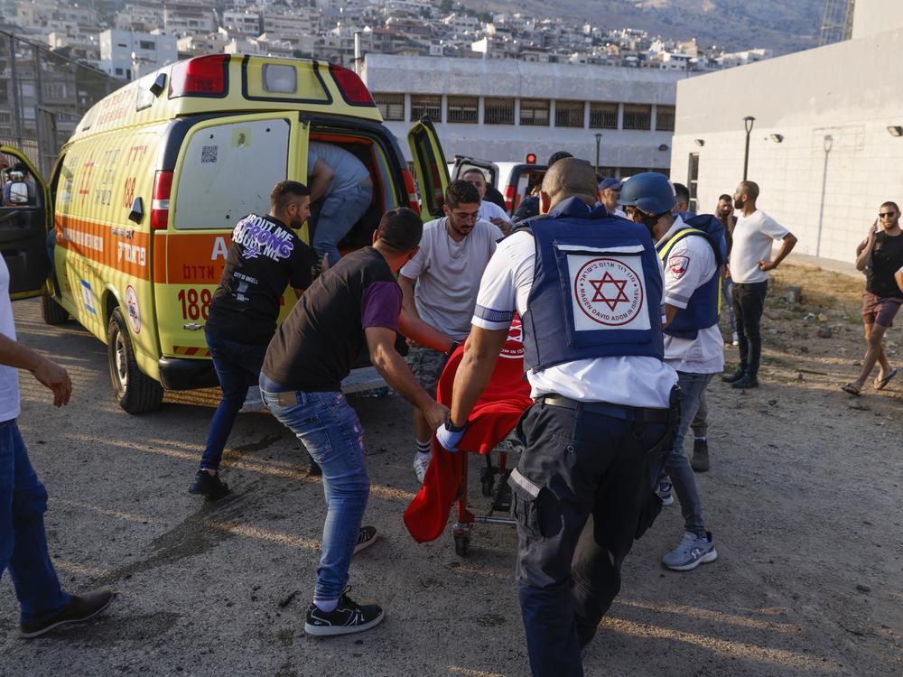 Israeli security forces and medics transport casualties along with local residents, at a site where a reported strike from Lebanon fell in Majdal Shams village in the Israeli-controlled Golan Heights area on Saturday.