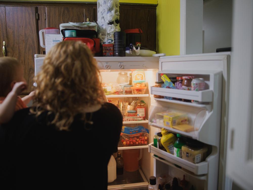 Annalise and Ellie Currence stand at the fridge, while deciding what to eat for dinner at their home in Belton, Mo., on July 17.