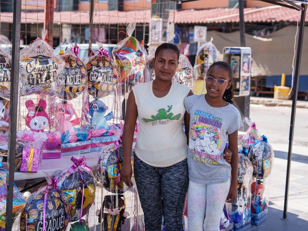 María Alejandra Amaris, 30, from Venezuela, poses for a portrait with her daughter on the plaza in Ciudad Juárez, Chihuahua state, Mexico on Saturday, June 29, 2024. Amaris is working for a store to sell graduation gifts which can help her pay for daily needs while waiting for an appointment via the CBP One application.  