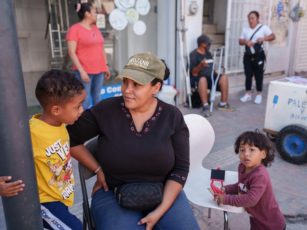 Yasmelin Velazquez, 35, from Venezuela sits with her sons (from left) Jordan and Jeremias Velazquez while selling souvenirs in Ciudad Juárez, Chihuahua state, Mexico, on Saturday. Velazquez is part of a growing number of migrants staying in Juárez and working while trying to get an appointment via the CBP One app.   