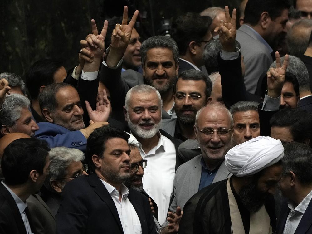 Palestinian Hamas chief Ismail Haniyeh, center, flashes a victory sign as he is surrounded by a group of Iranian lawmakers after the conclusion of the swearing-in ceremony of newly-elected Iranian President Masoud Pezeshkian at the parliament in Tehran, Iran, Tuesday, 30, 2024.