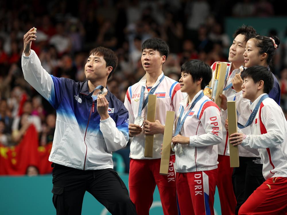 Lim Jong-hoon of South Korea takes a selfie with North Korean silver medalists Kim Kum-yong and Ri Jong-sik, center, with Chinese gold medalists Wang Chuqin and Sun Yingsha flanking South Korean Shin Yu-bin.