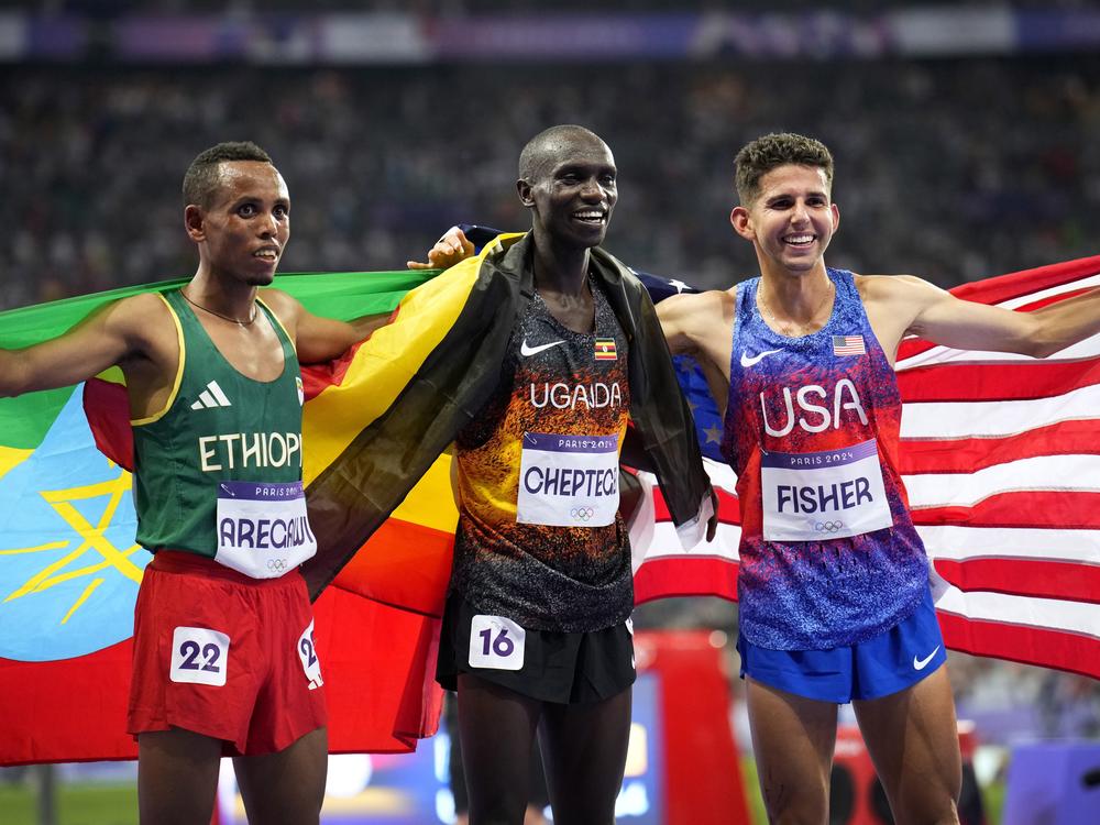 Gold medalist Joshua Cheptegei, of Uganda, poses with silver medalist Berihu Aregawi, of Ethiopia, left, and bronze medalist Grant Fisher, of the United States, after the men's 10,000-meter final at the 2024 Summer Olympics, Friday, in Saint-Denis, France.