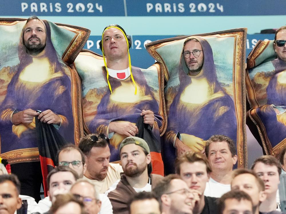 Fans dressed as Mona Lisa watch a preliminary handball match on Monday.